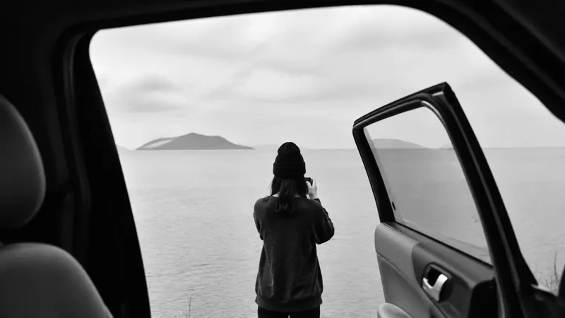 从车门望向海面的黑白旅行画面